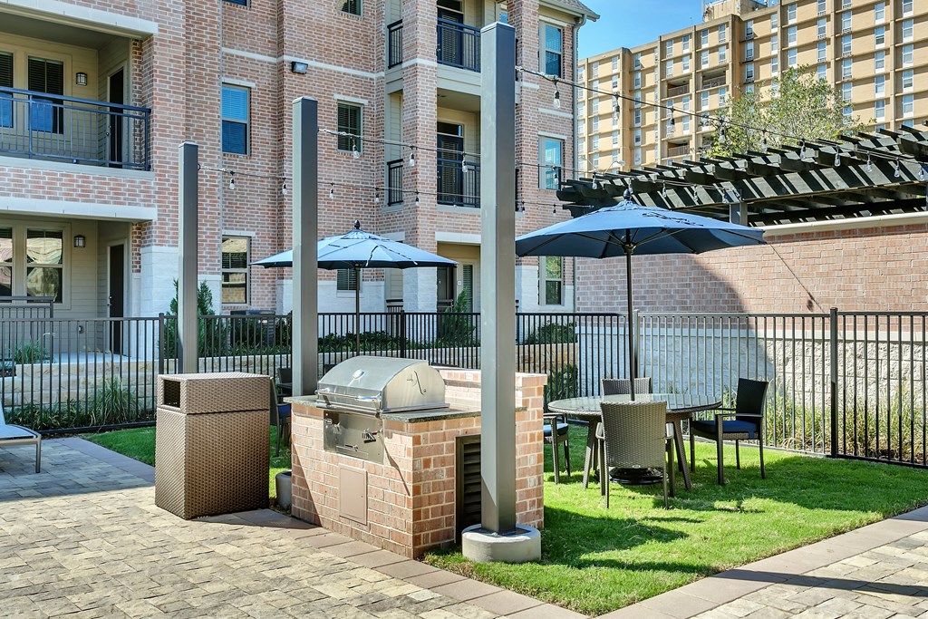 a patio with a grill and a table with umbrellas