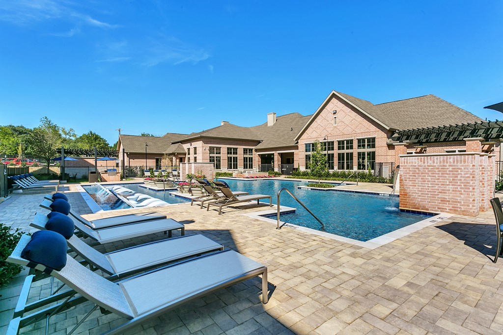 a swimming pool with lounge chairs and a house in the background