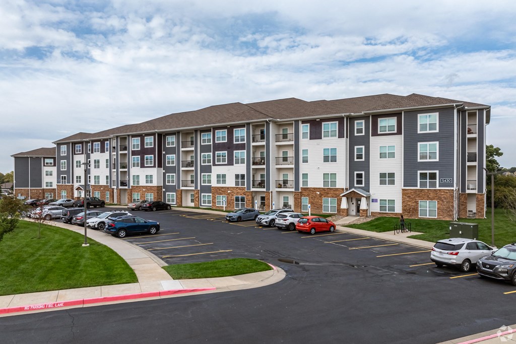 a large apartment building with cars parked in a parking lot