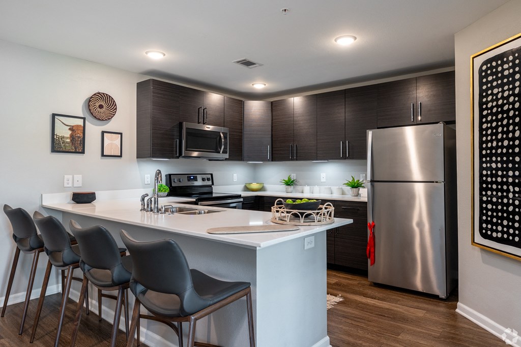 a kitchen with a large island and stainless steel refrigerator