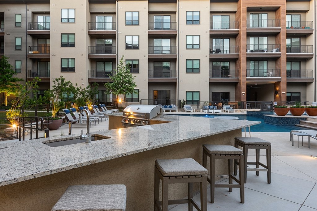 a pool area with stools in front of an apartment building