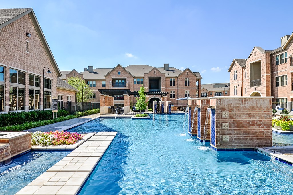 a swimming pool with brick buildings and a water fountain