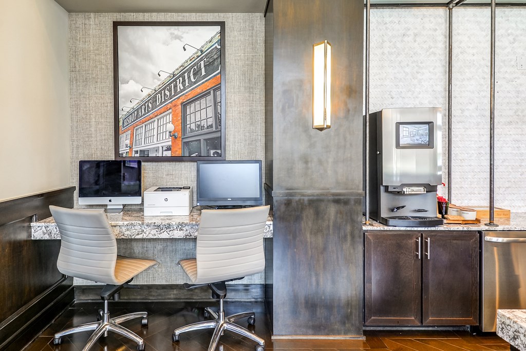 a business desk with two computers and a printer in a hotel room