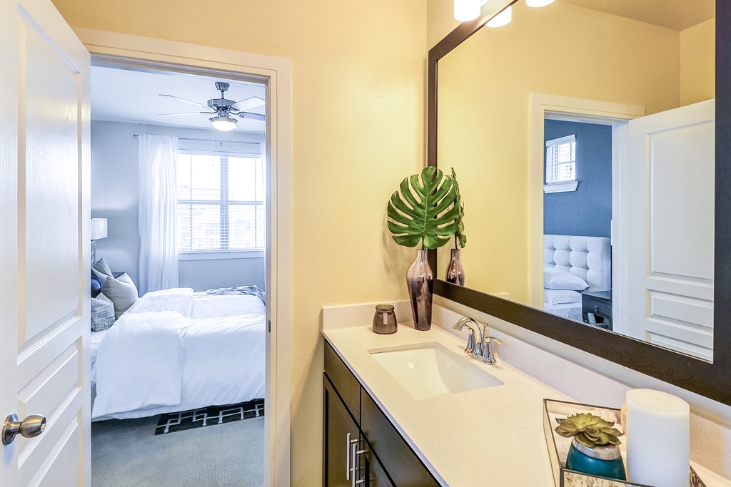 a bathroom with a mirror and a sink and a bedroom