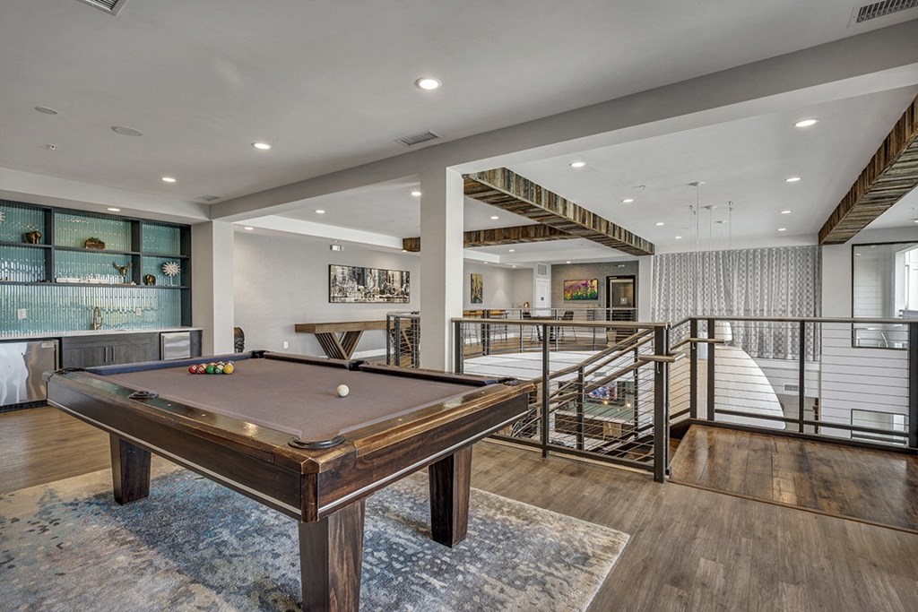 a pool table in a living room with a bar and a staircase