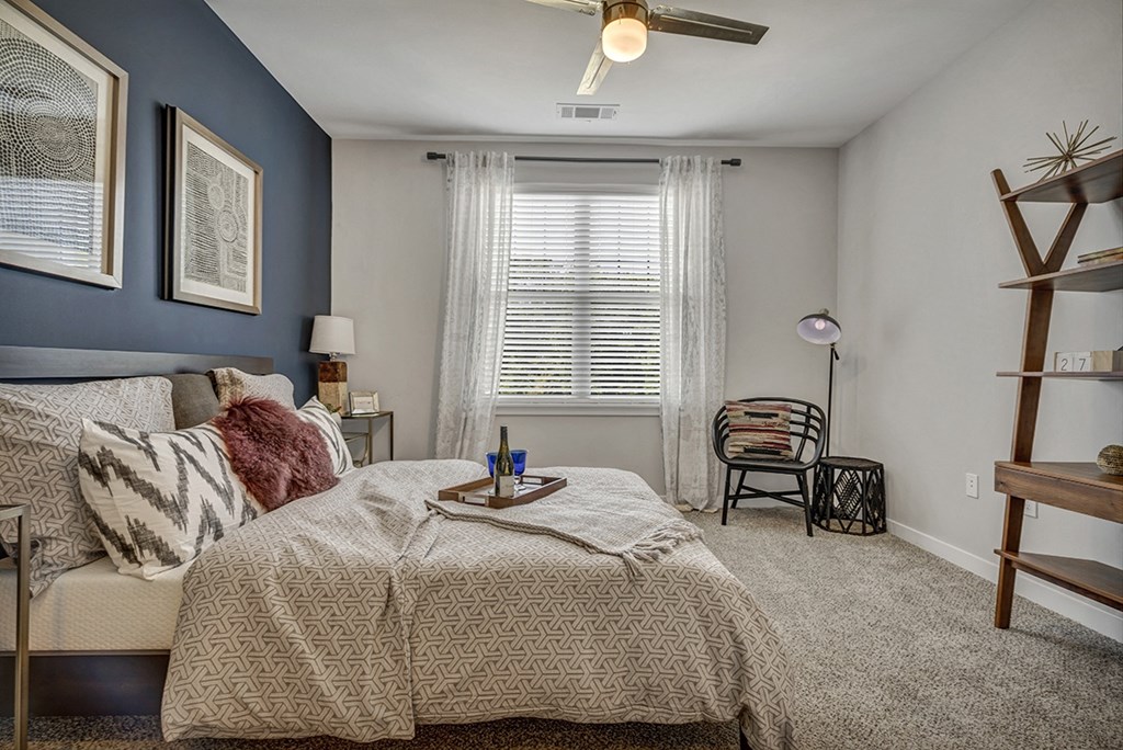 a bedroom with a bed and a chair and a ceiling fan