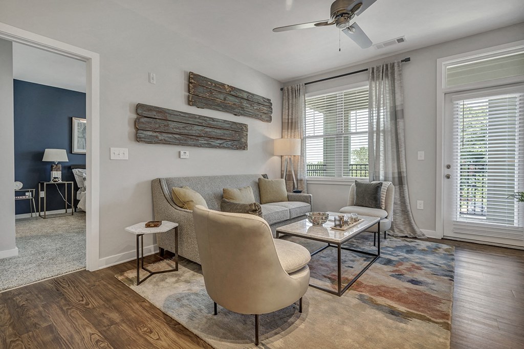 a living room with a couch and chairs and a ceiling fan