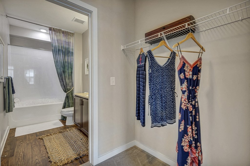 a bathroom with a shower and a closet with clothes hanging in it
