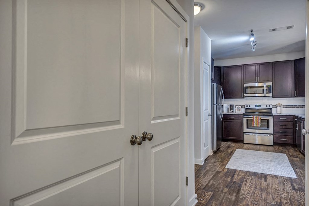 a door leading into a kitchen with a stove and a refrigerator