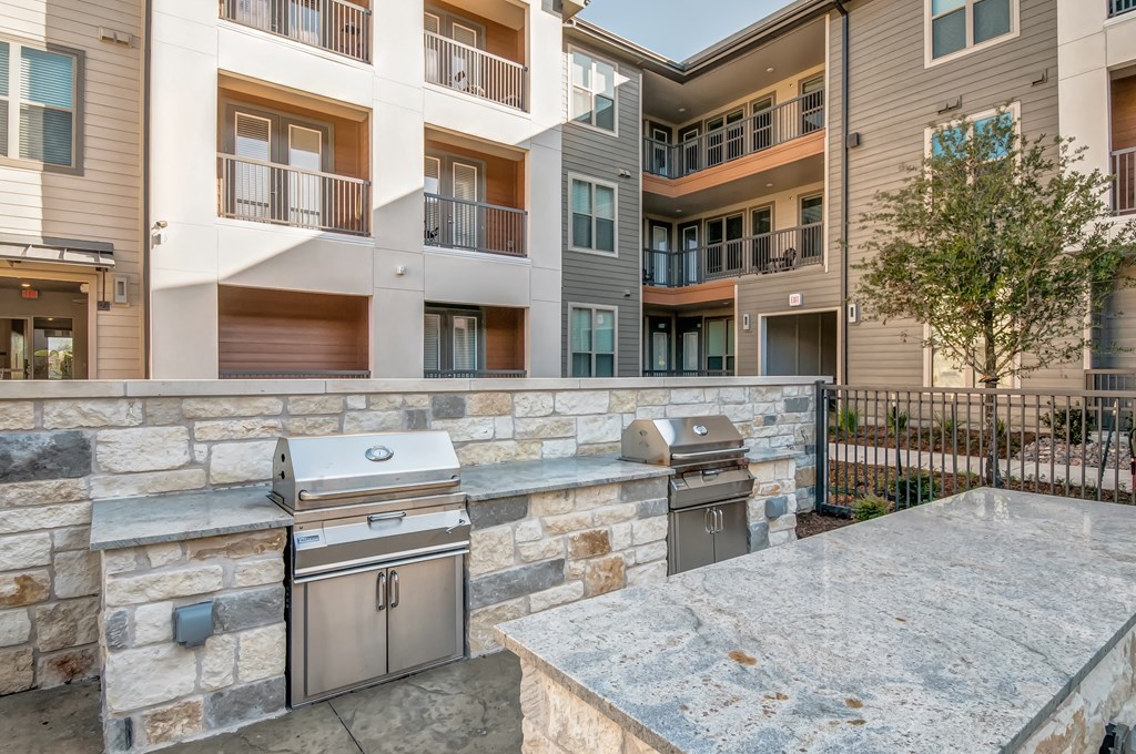 an outdoor kitchen with stainless steel appliances and a stone wall