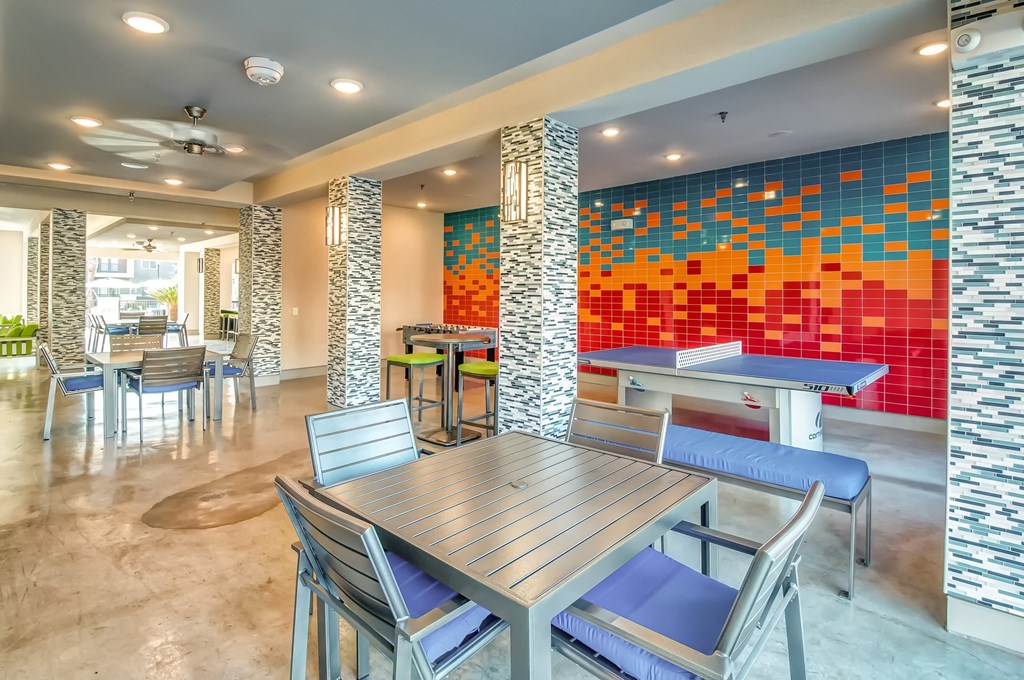 a dining area with tables and chairs and a colorful wall with tiles
