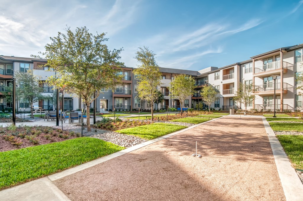 a pathway leading to an apartment building with grass and trees