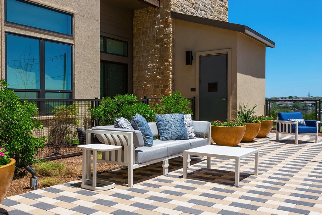 an outside patio with chairs and tables and potted plants