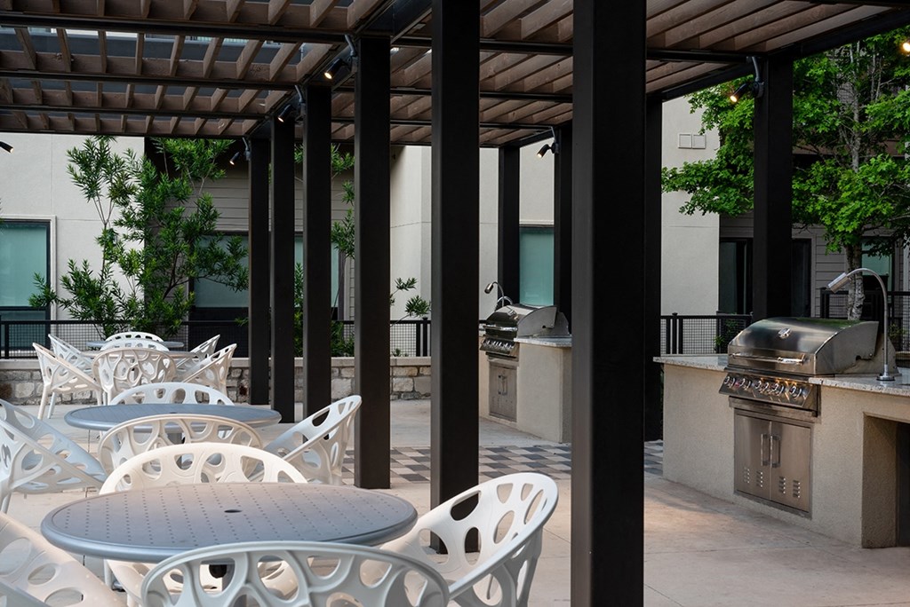 a patio with tables and chairs and a grill