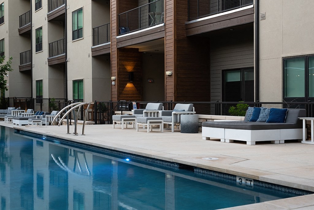 a swimming pool with chairs and tables next to a building
