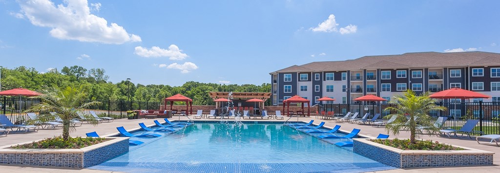 an outdoor swimming pool with blue lounge chairs and a building in the background