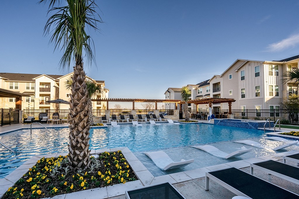 a large swimming pool with chaise lounge chairs and a palm tree