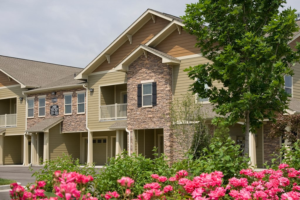 an apartment building with pink flowers in front of it