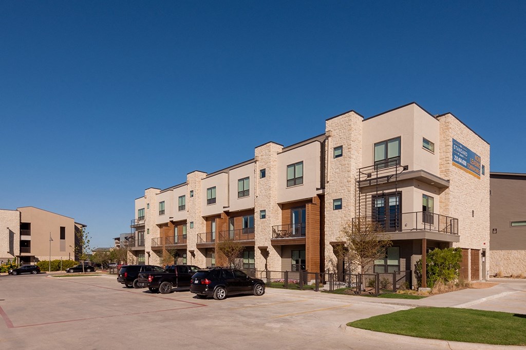 a row of apartment buildings with cars parked in front of them