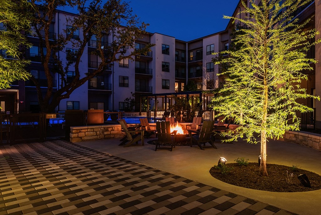 an outdoor area with a fire pit and trees at night
