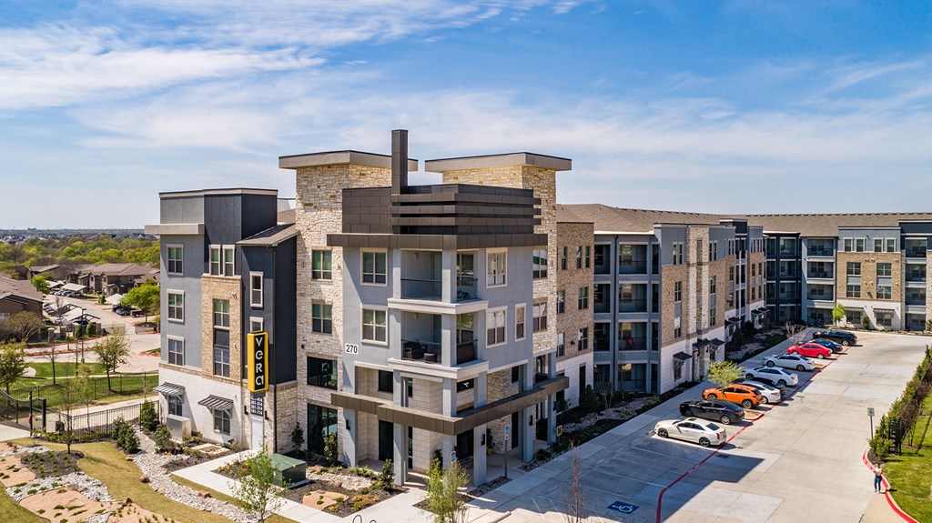 an aerial view of a large apartment complex with cars parked on the side of the road