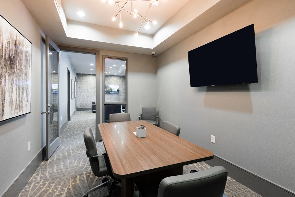 a meeting room with a table and chairs and a tv on the wall