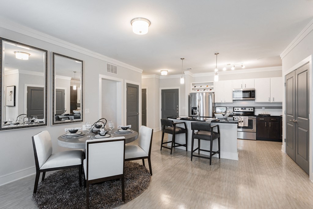 a dining area with a table and chairs and a kitchen in the background