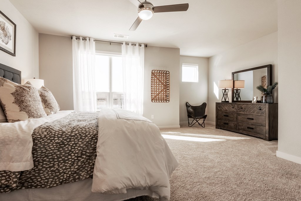 a bedroom with a bed and a dresser and a ceiling fan
