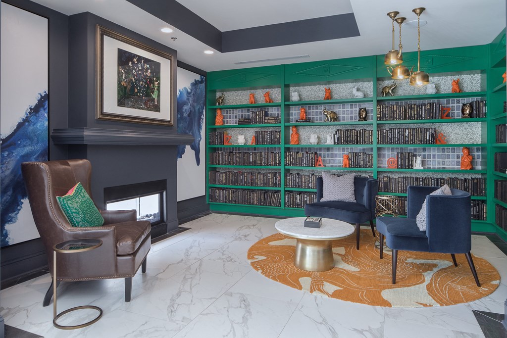 a library with chairs and a table and a fireplace