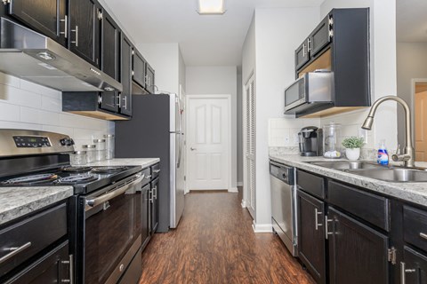 a kitchen with black cabinets and stainless steel appliances and a wood floor