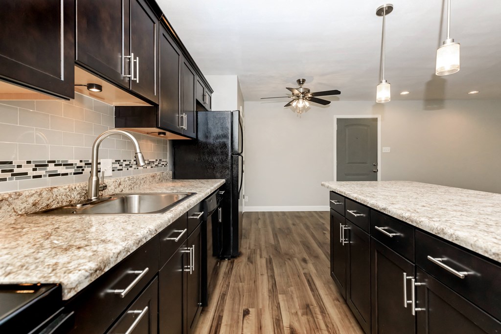 a kitchen with dark cabinets and white countertops