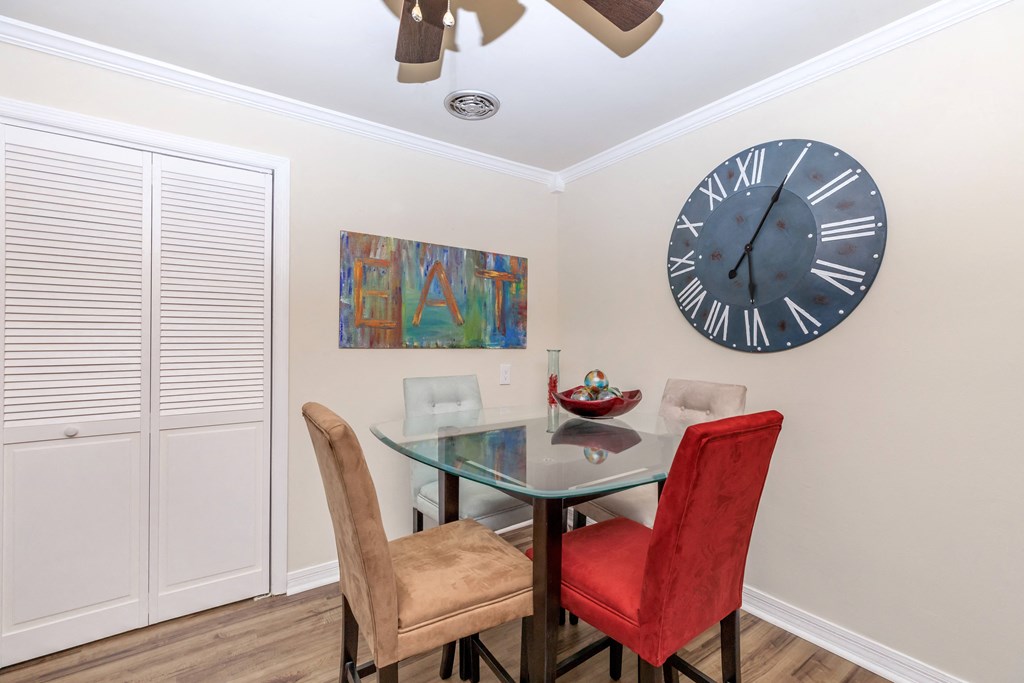 a dining room with a glass table and chairs and a large clock on the wall
