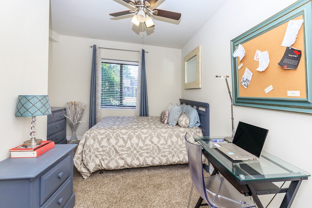 a bedroom with a bed and a desk with a laptop