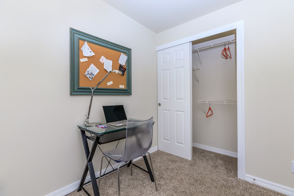 a small desk with a laptop and a lamp in the corner of a room with a closet
