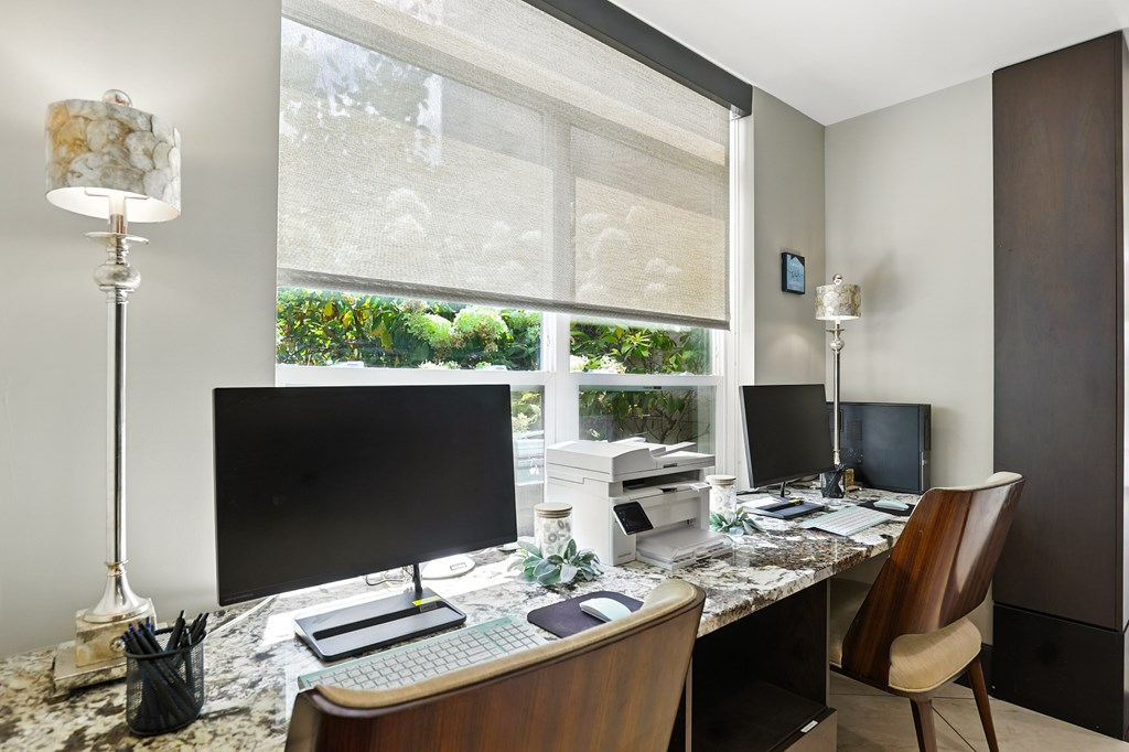 A modern home office with a large window and two monitors at Alinea Town and Country Luxury Apartments in Des Peres MO 63131.