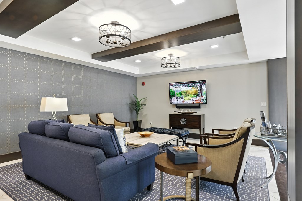 A living room with a blue couch, a chair, a coffee table, and a television at Alinea Town and Country Luxury Apartments in Des Peres MO 63131..