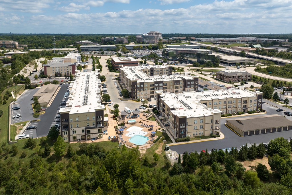 A large apartment community of buildings with a pool in the middle at Alinea Town and Country Luxury Apartments in Des Peres MO 63131..