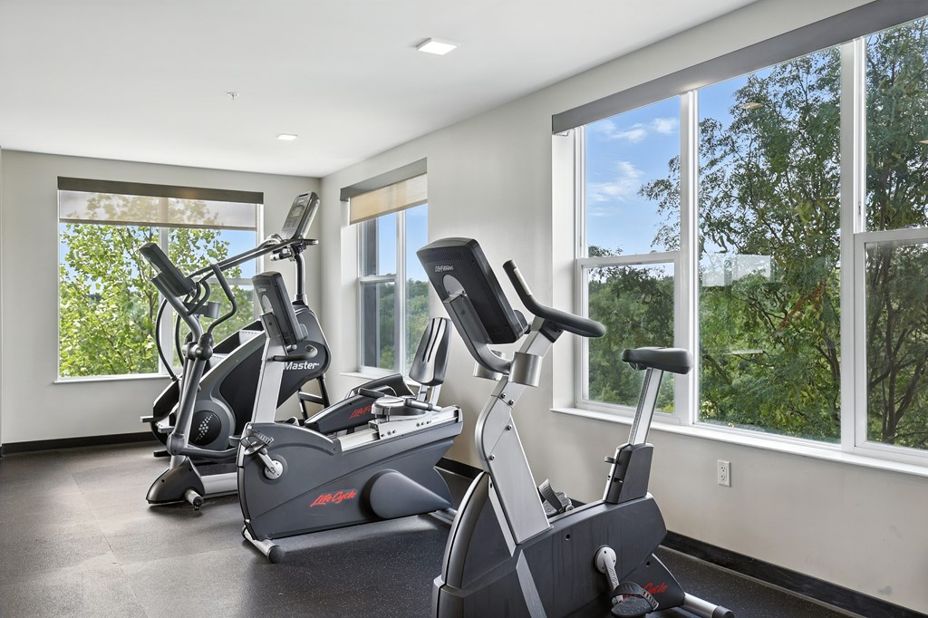 A room with a treadmill, a stationary bike, and a rowing machine at Alinea Town and Country Luxury Apartments in Des Peres MO 63131.