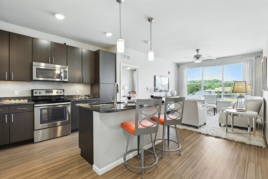 A modern kitchen with a bar stool and a dining table at Alinea Town and Country Luxury Apartments in Des Peres MO 63131.