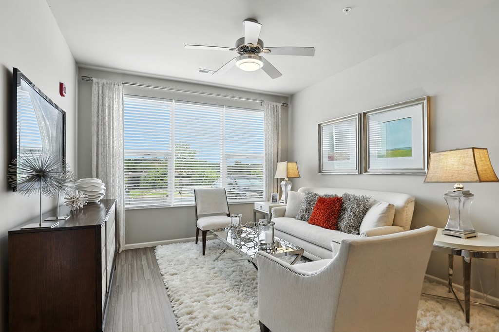 A living room with a white couch, a coffee table, and a ceiling fan at Alinea Town and Country Luxury Apartments in Des Peres MO 63131.