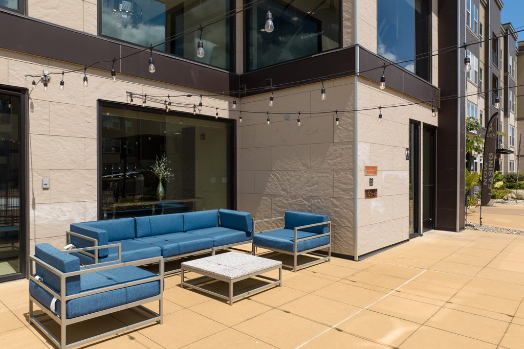 A patio with a blue couch and a table at Alinea Town and Country Luxury Apartments in Des Peres MO 63131..