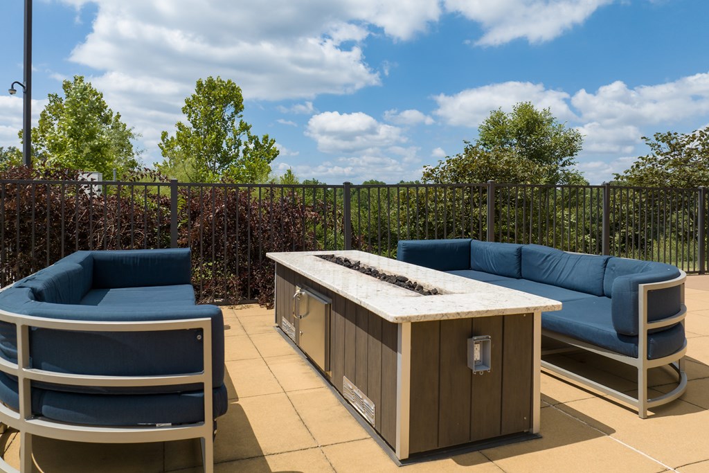 A blue couch and a wooden table are on a patio at Alinea Town and Country Luxury Apartments in Des Peres MO 63131..