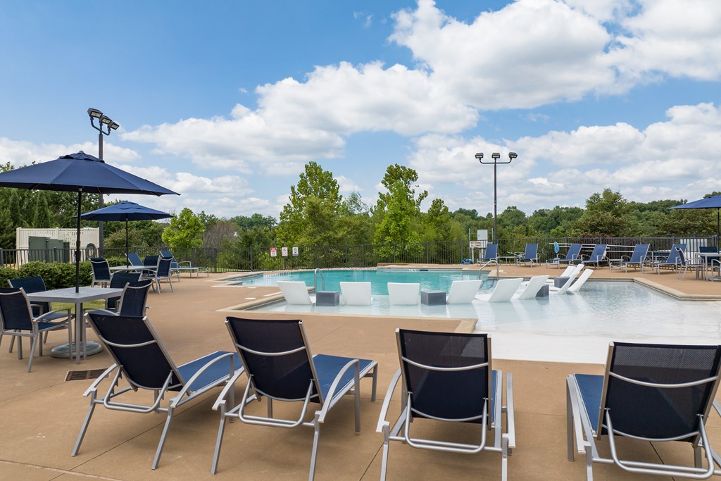 A pool area with chairs and umbrellas at Alinea Town and Country Luxury Apartments in Des Peres MO 63131.