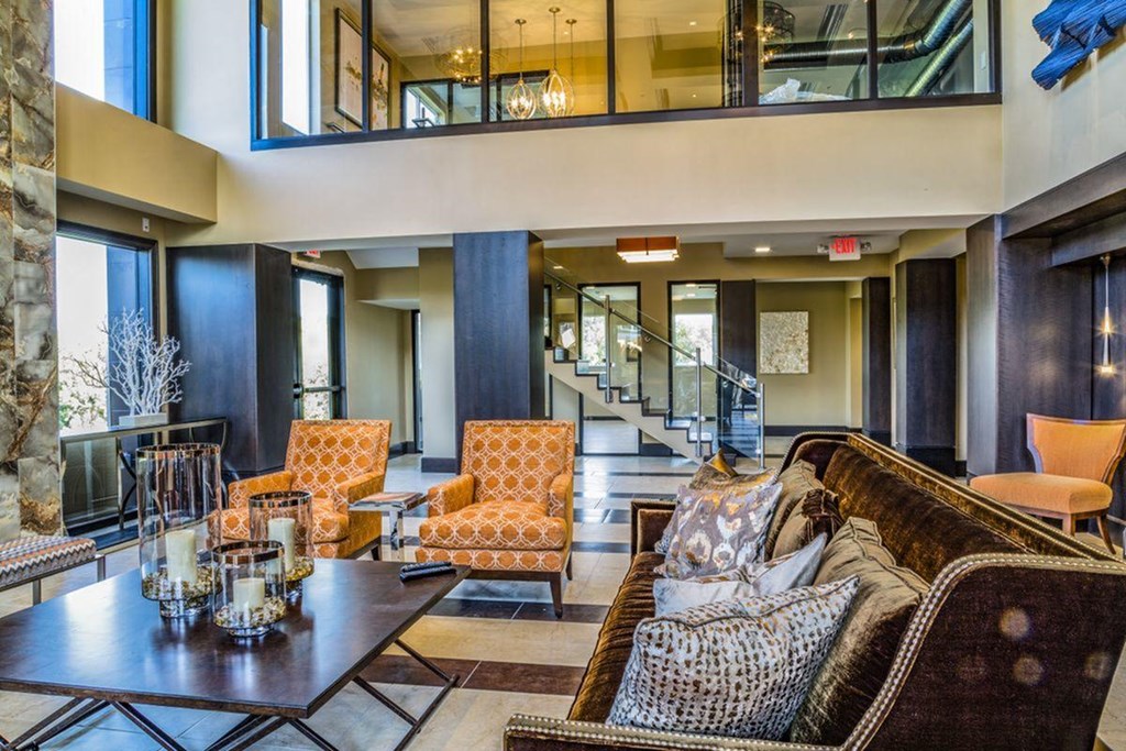 a living room with a couch and chairs and a staircase