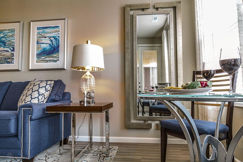 a living room with a blue couch and a table and a mirror