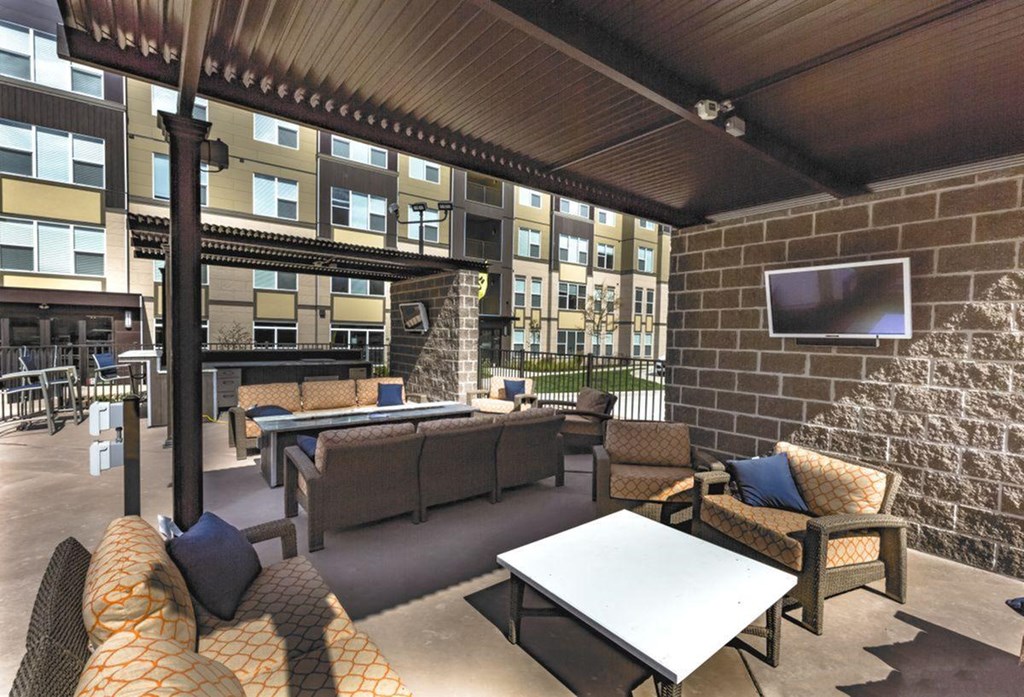 a covered patio with a grill, furniture and a television