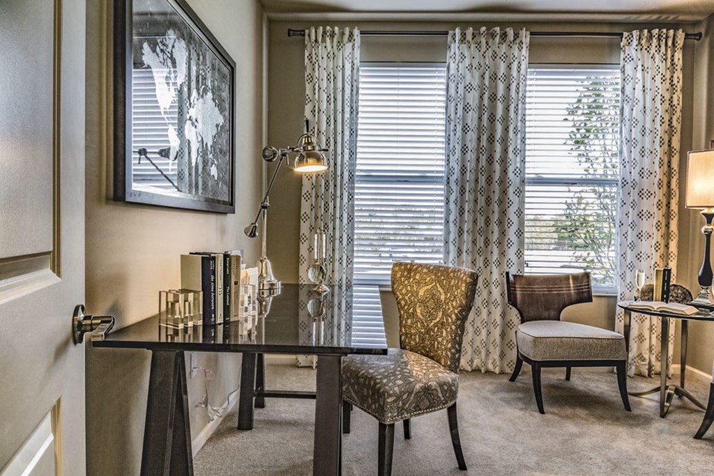 a home office with a desk and chairs and a window