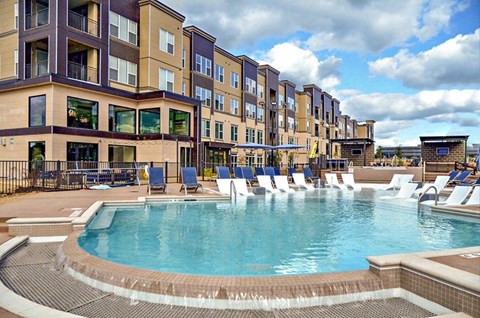 a swimming pool with chairs in front of a building