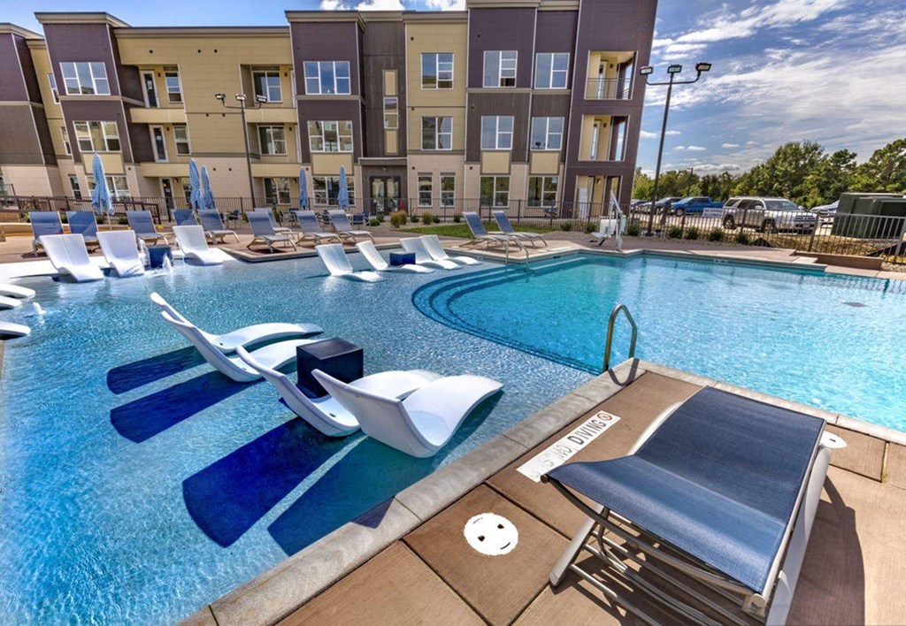 an outdoor pool with lounge chairs and a resort style swimming pool