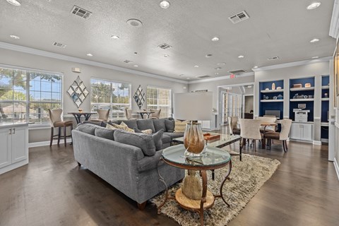 A living room with a grey couch and a glass coffee table.